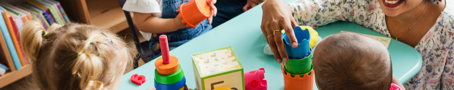 Image of children seated at table with educator stacking cups