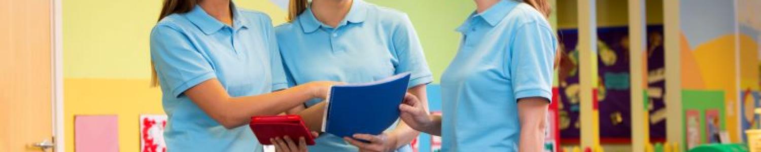 Three educators in a conversation, one is holding a folder