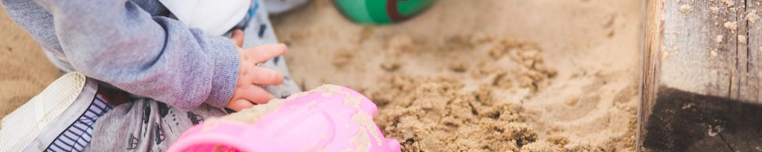 Child playing in a sand pit with buckets