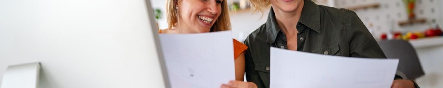 Two educators enthusiastically working in front of a laptop and and sheets of paper
