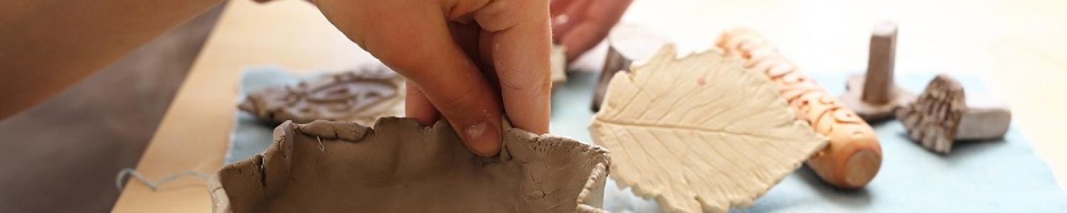 Child's hands creating a clay pinch pot