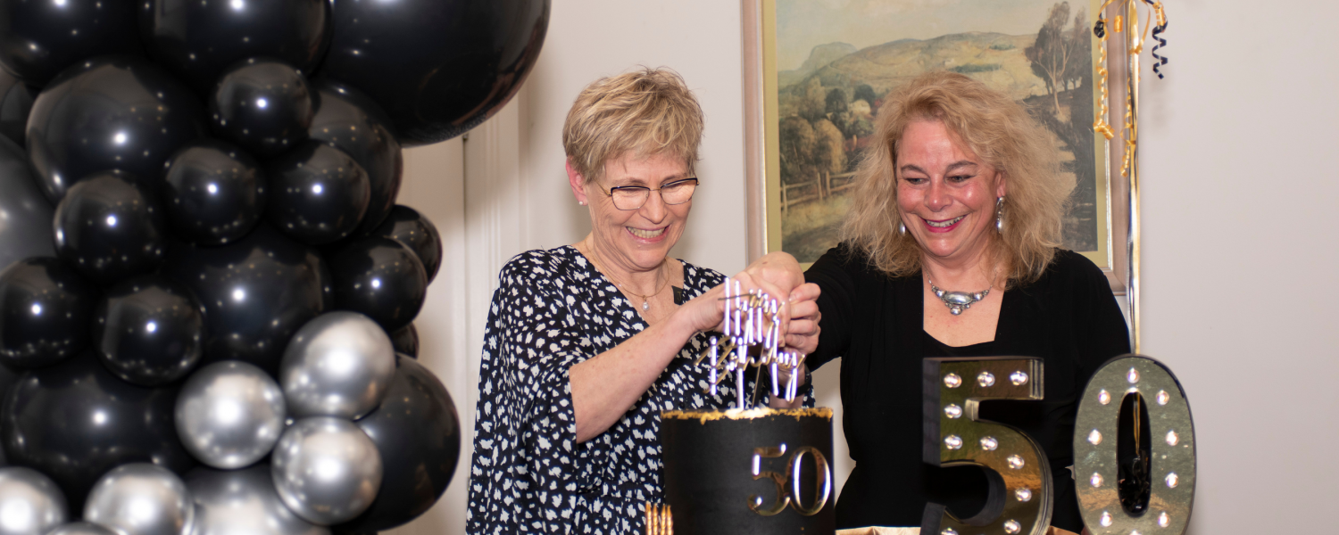 Julie Price and Linda Davison cut 50th birthday cake.