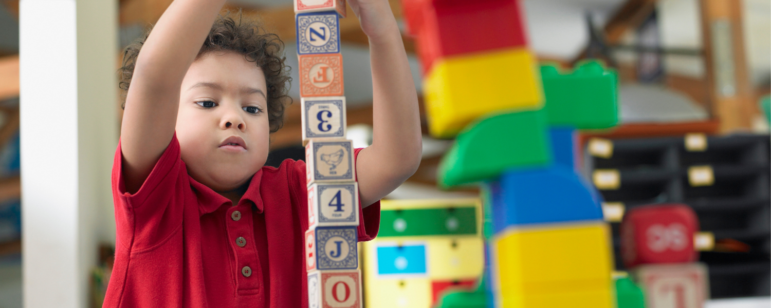 A young boy building a tower with building blocks