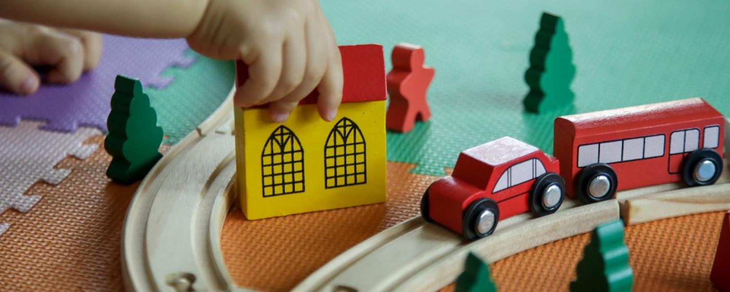 Child playing with a wooden train set on the floor