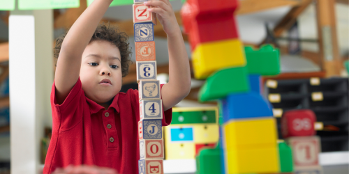 A young boy building a tower with building blocks