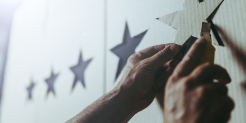 4 cardboard stars hung on wall. A pair of hands looks to be placing a fifth star.