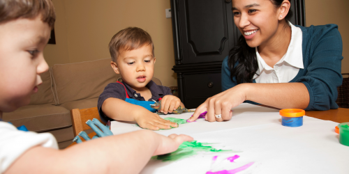 A woman and two children sitting around a table painting