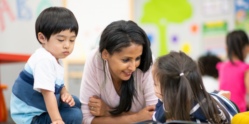 educator lying on floor with children on either side