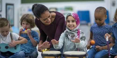 Child in head scarf playing bongo drums