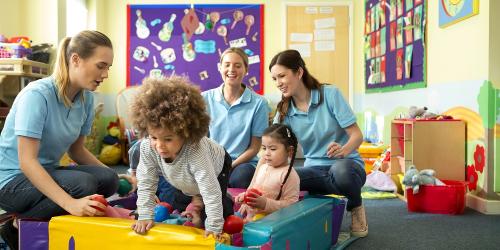 Educators and children playing on soft equipment