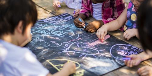 Group of kindergarten children drawing outdoors