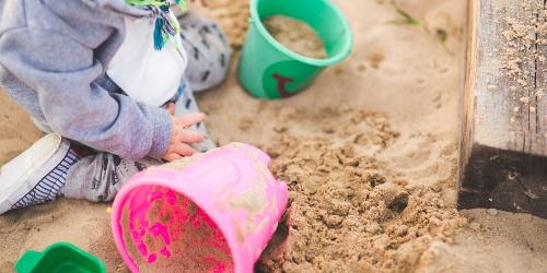Child playing in a sand pit with buckets