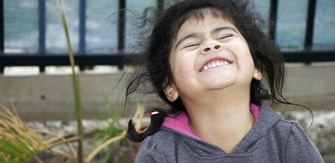 Joyful child with head titled to the sky with eyes closed