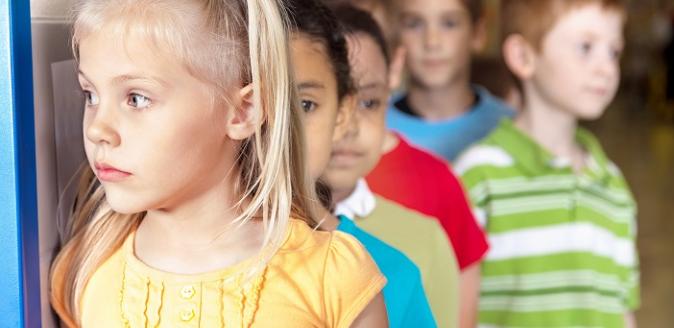 Young, school-aged children lining up behind one another