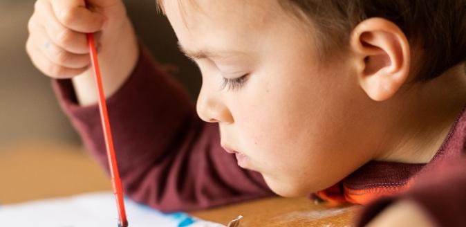 Young child concentrating on painting with poster paint