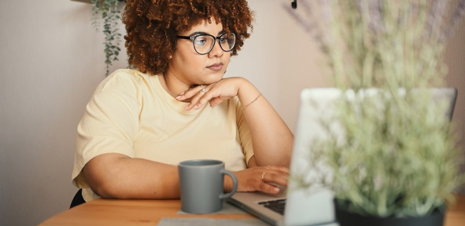 Educator working at a desk with a hot drink and a laptop