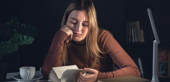 Despondent looking educator at a desk flipping through a book