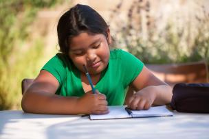 School aged girl writing in a notebook