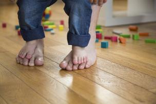 A child's bare feet standing on the top of an adult's bare feet