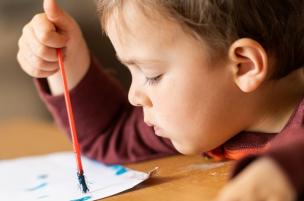 Young child concentrating on painting with poster paint