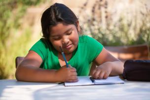 School aged child writing in a notebook