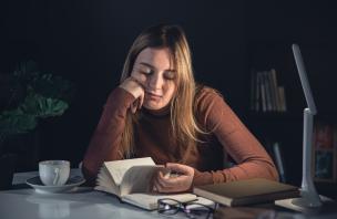 Despondent looking educator at a desk flipping through a book